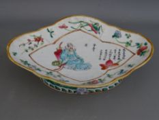 A 19th CENTURY CHINESE FAMILLE ROSE PEDESTAL DISH with decorated central panel of a seated deity and