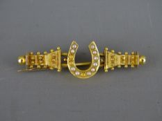 A FIFTEEN CARAT GOLD BROOCH with seed pearl encrusted horseshoe, 4 grms