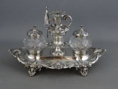 A VICTORIAN TWO BOTTLE WITH CHAMBERSTICK INKSTAND raised on four decorative feet, raised leaf border