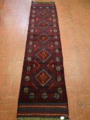 A MESHWANI CARPET RUNNER, red ground with block cross pattern border and central repeating diamond