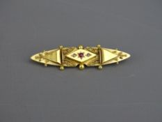 A FIFTEEN CARAT GOLD BAR BROOCH with filigree decoration and centre ruby, 2.5 grms