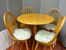 A modern lightwood circular top dining table with four stick back chairs and a portable radiator E/