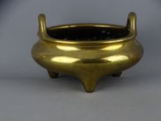 A Chinese polished bronze censor with raised hoop handles on three feet, Xuande six character base