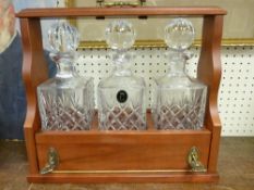 Modern mahogany effect three bottle tantalus with hand cut 24% lead crystal bottles and stoppers,