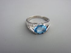 Eighteen carat white gold dress ring with centre oval blue topaz and flanking tiny diamonds, each