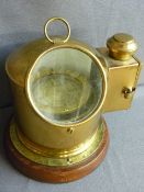 Brass ship's type gimbal compass with side lamp, mounted on a circular wooden base, 27 cms high
