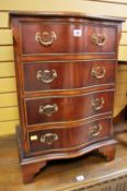 A GOOD REPRODUCTION SERPENTINE FRONT SMALL CHEST of four drawers with brass handles