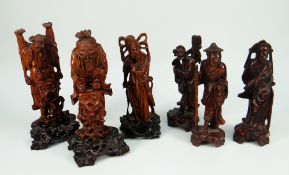 A GROUP OF SIX ORIENTAL CARVED WOODEN FIGURES on stands