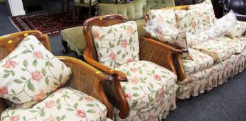 A THREE PIECE BERGERE SUITE comprising three seater sofa and a pair of armchairs and having later