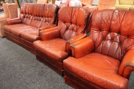 A C20TH LEATHER THREE PIECE SUITE in red buttoned upholstery comprising three-seater settee and pair