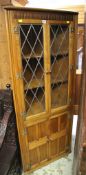 A REPRODUCTION PANELLED & LUNETTE CARVED STANDING CORNER CABINET with cupboard base