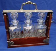 A MID-C20TH TANTALUS with key, three bottles with wine labels