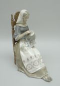 A LLADRO PORCELAIN SCULPTURE OF A SEATED LADY needle-working and wearing a decorative apron, 30cms