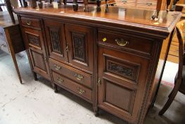 AN EDWARDIAN SIDEBOARD with an arrangement of drawers and cupboards and having carved panels