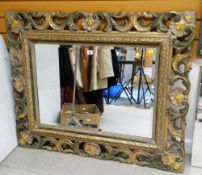 A LARGE BEVELLED WALL MIRROR in a painted scrolling and leaf form open-carved frame
