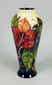 A MOORCROFT POTTERY BALUSTER VASE in the 'Simeon' pattern of flowers and leaves (boxed), 20cms high
