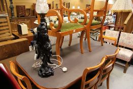 A YEW-EFFECT DINING TABLE with six chairs and a carved figure of a Chinese scholar with table lamp