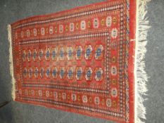 MAINLY RED GROUND INDIAN WOOLEN RUG, lozenge pattern and similar border (worn to centre), 123 x