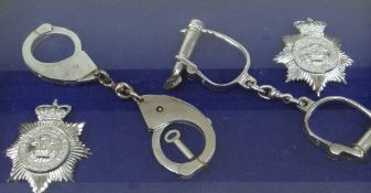 FRAMED DISPLAY OF POLICE FORCE HARDWARE comprising two sets of steel handcuffs and two South Wales