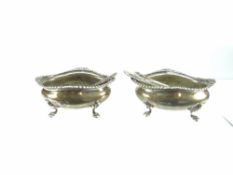 PAIR OF SILVER SALTS & MATCHING SPOONS of oval form on four pad feet and with feathered decorative