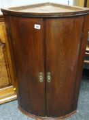 19TH CENTURY MAHOGANY BOW-FRONT HANGING CORNER CUPBOARD the interior with two lobed shelves, brass