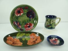 FOUR ITEMS OF MOORCROFT POTTERY comprising mug, plate, small circular footed dish and larger oval