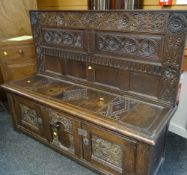 GOOD ANTIQUE OAK SETTLE with a lift up seat and extensive carving to the back and carved three panel