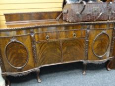 IMPOSING ANTIQUE FLAME MAHOGANY RAIL BACK SIDEBOARD with bowed flanking cupboards and carved