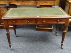 NEAT EDWARDIAN MAHOGANY GREEN LEATHER TOP DESK with two drawers and reeded legs with castors,