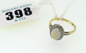 18CT YELLOW GOLD & PLATINUM DIAMOND & OPAL RING having an oval opal surrounded by small diamonds and