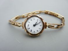 A LADY'S 9CT GOLD ENCASED WRISTWATCH having a circular dial and with expanding 9ct gold bracelet,