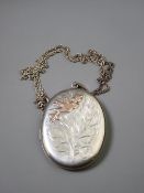 A LARGE OVAL PLAIN BACKED SILVER PHOTO LOCKET with bird and leaf decoration to the front and with
