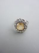 AN OVAL PLATINUM DRESS RING having a centre lemon yellow citrine with fourteen surrounding small