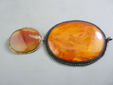 A LARGE OVAL AMBER STYLE PENDANT on soft metal, 7 x 5.5cms and a small oval agate brooch in a yellow