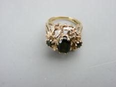 A LARGE 9CT GOLD DRESS RING with graduated shoulders and large medium green centre peridot with