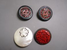 A CIRCULAR FLORAL CINNABAR BROOCH, a mother of pearl brooch with star and scroll pattern and a