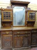 AN EDWARDIAN OAK BREAK FRONT MIRRORED BACK SIDEBOARD having a carved detail, four drawers, four