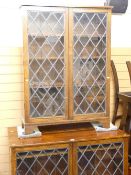 A SET OF THREE POLISHED BOOKCASES, floor standing, each with two leaded and latticed glazed doors