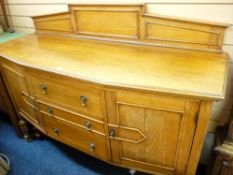 A WELL PRESENTED BLONDE OAK RAIL BACK SIDEBOARD, the shaped front having three central drawers and