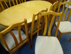 A MID CENTURY STYLE LIGHT TEAK EXTENDING DINING TABLE with flip out centre section and eight