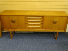 A MID CENTURY SIDEBOARD by Elliots of Newbury with sliding front doors and centre three drawer