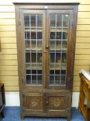 AN ANTIQUE BOOKCASE CUPBOARD with upper leaded glazed doors and lower cupboard doors with carved fan