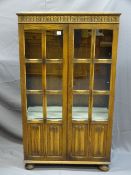 A VINTAGE OAK DISPLAY CABINET with twin glazed panel and linenfold carved doors, on bun feet, 135cms
