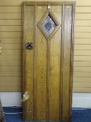 A VINTAGE OAK HEAVY GAUGE HANDLE ENTRANCE DOOR with stained glass diamond shape panel and iron pull,