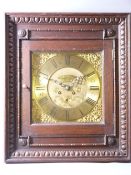 A MATTHEW BUSHELL SQUARE BRASS CLOCK DIAL with wall clock movement housed in a glazed door front