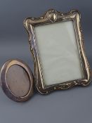 A HALLMARKED SILVER PHOTO FRAME along with a smaller oval shaped hallmarked silver frame