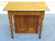A PITCH PINE ALTAR TABLE on turned supports with wine storage cupboard below, 91cms width x 81cms