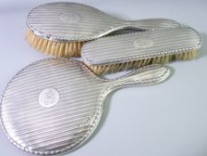 A SILVER THREE PIECE HAND MIRROR WITH BRUSHES DRESSING TABLE SET, Birmingham 1917 and 18 dates