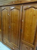 HONEY PINE TRIPLE WARDROBE with drawer base, together with a matching two drawer dressing table