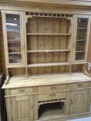 A STRIPPED PINE DRESSER with centre shelves flanked by glazed cupboards, and four drawer two